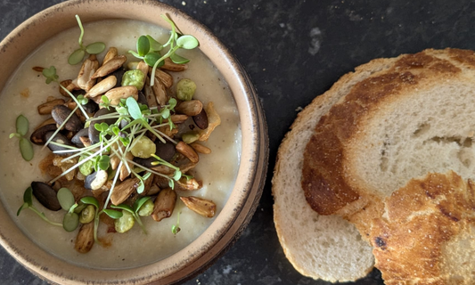 Creamy fennel and celeriac soup garnished with broccoli microgreens, served in a rustic bowl.