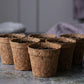 Teeny Greeny coir pots empty group of six on dark slate background showing natural coconut fibre texture