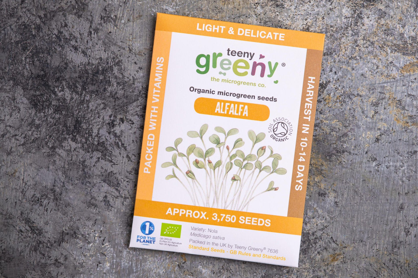 Teeny Greeny organic alfalfa microgreen seed packet flat lay on stone surface