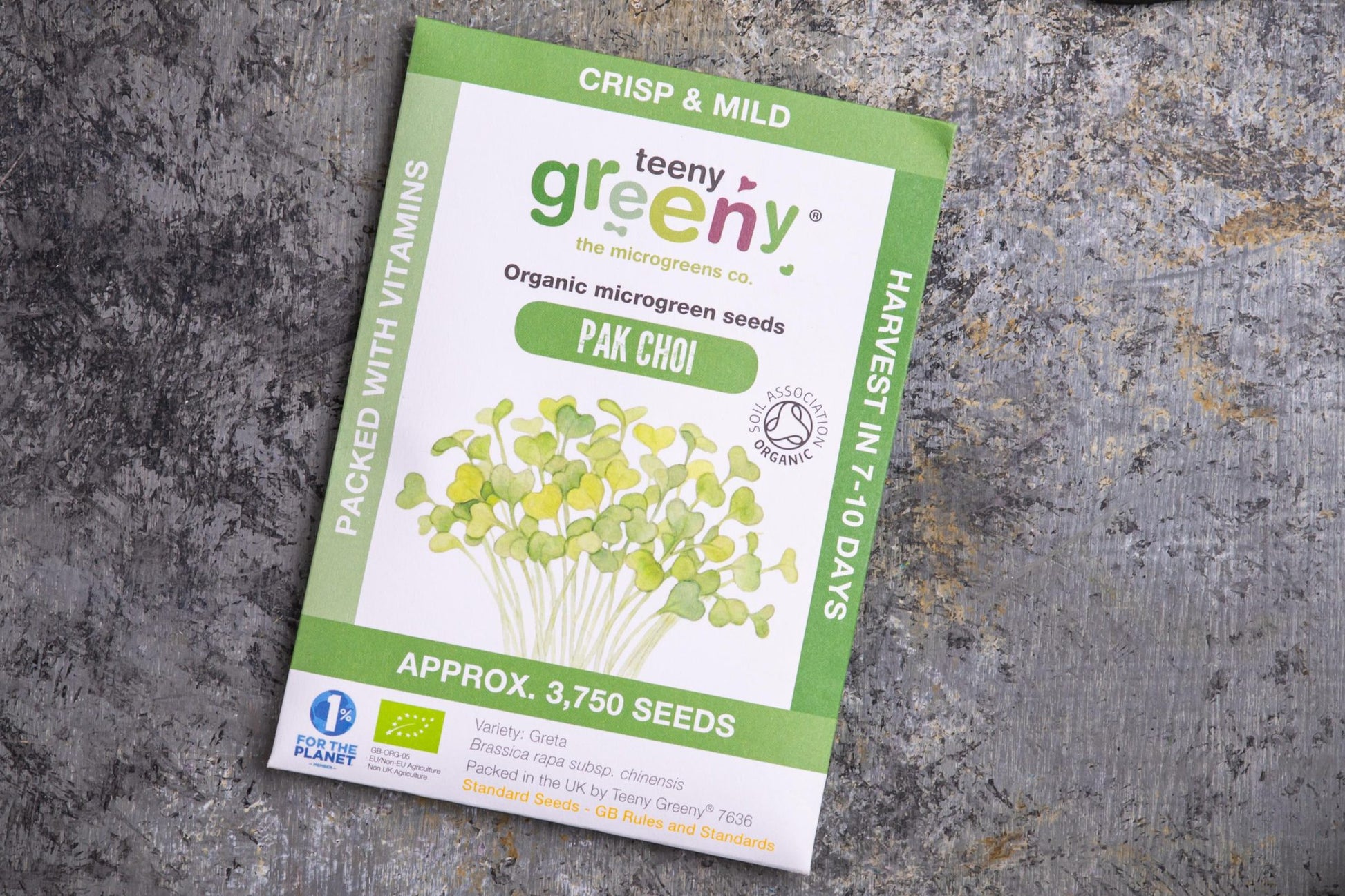 Teeny Greeny organic pak choi microgreen seed packet flat lay on stone surface
