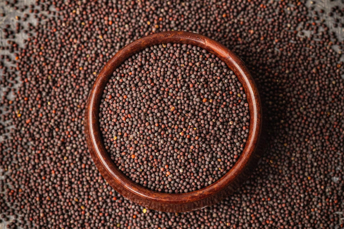 Teeny Greeny organic red mizuna microgreen seeds close up in wooden bowl
