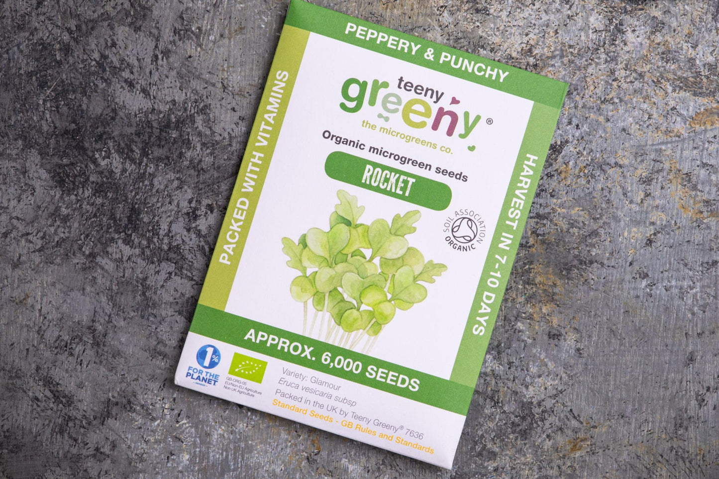 Teeny Greeny organic rocket microgreen seed packet flat lay on stone surface